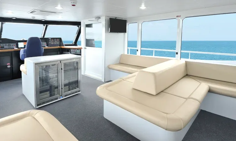 Cream lounge seating and large windows overlooking the ocean in the Captain's Lounge