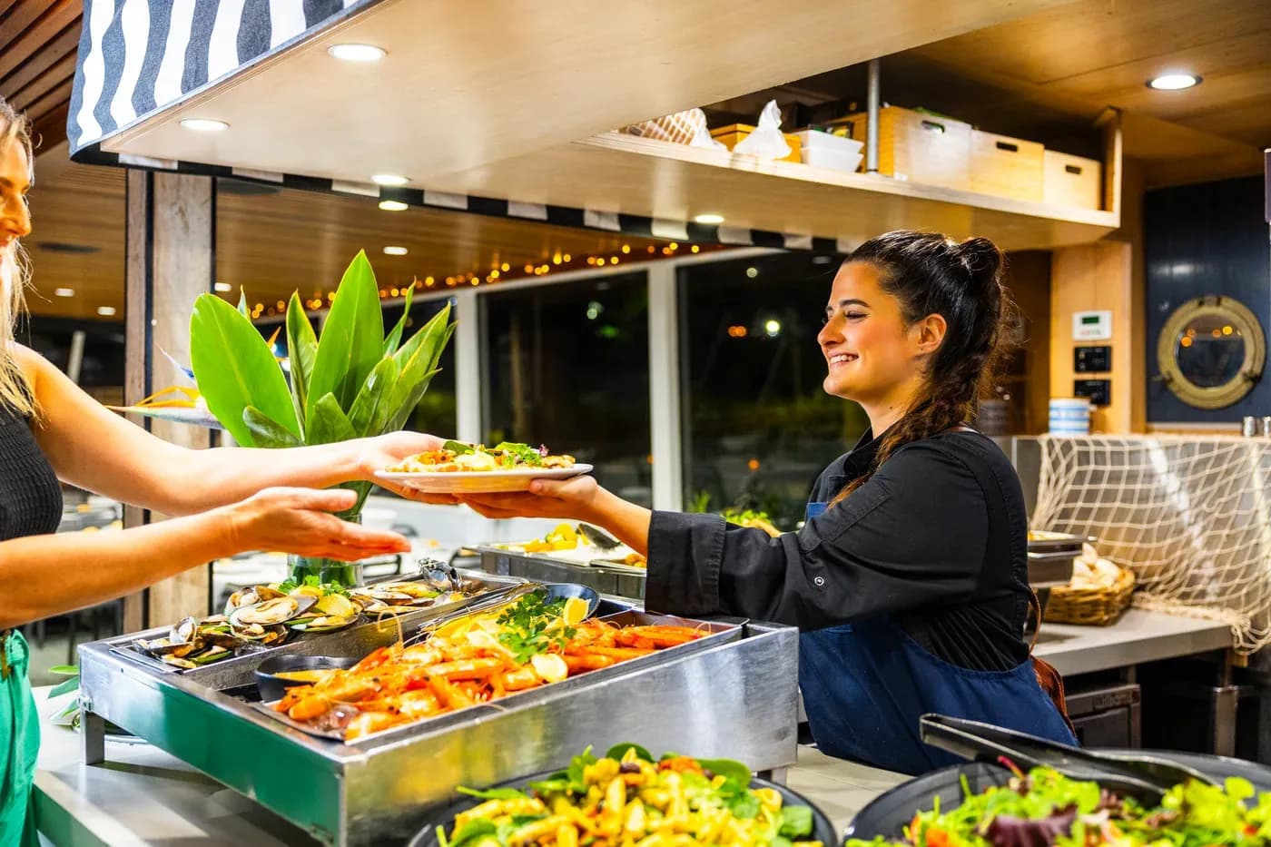 A crew member serving guests at the evening buffet