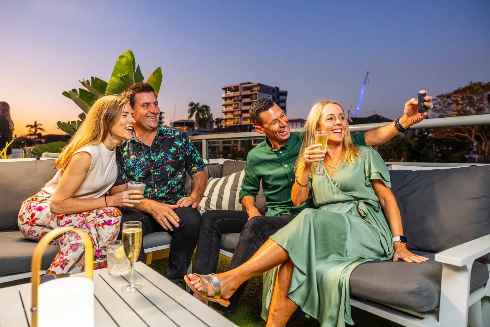 Four friends taking a photograph together on the open deck at sunset