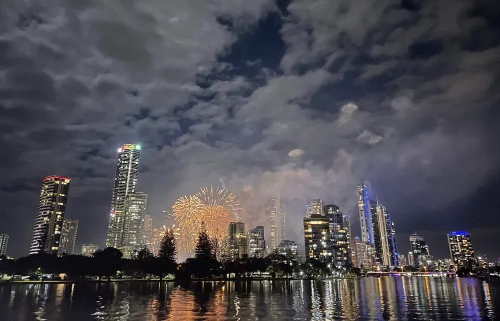 Fireworks over the illuminated city skyline and water