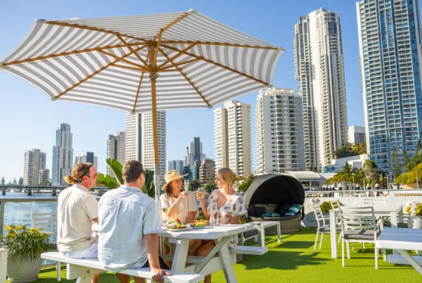 1. TheTourCollective SeaWorldCruises Gold Coast Buffet Lunch 4 guests on top deck dining under umbrella with Surfers Paradise in background TTC100608